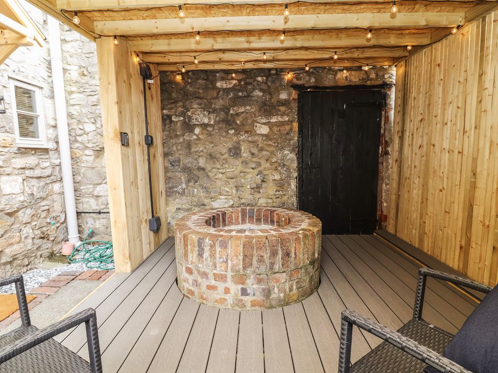 An outdoor seating area with a brick fire pit and wood flooring at The Ranch in Prestatyn