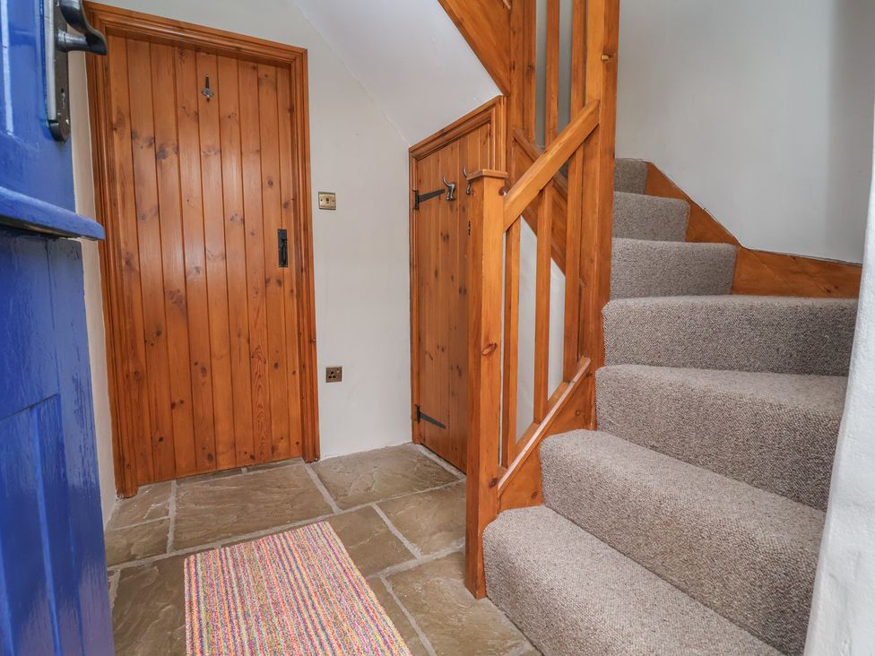 A hallway with stairs and a wooden door at The Ranch in Prestatyn