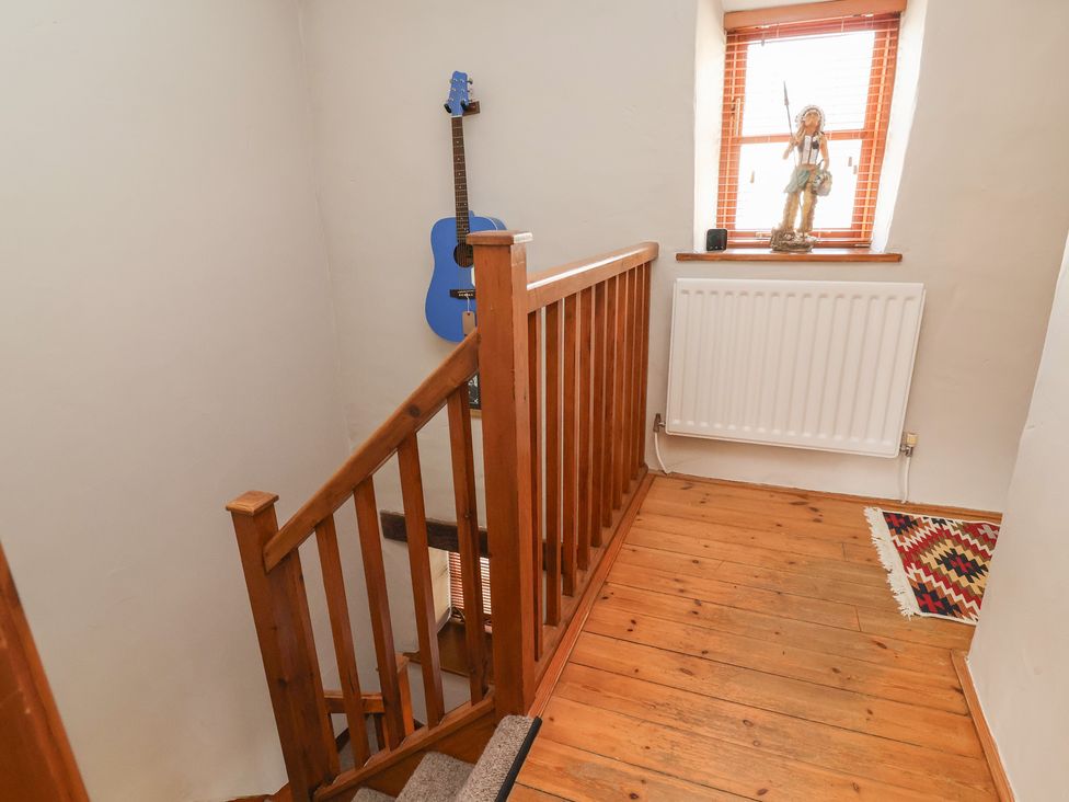 A hallway with a guitar on the wall and a figurine on the window sill at The Ranch in Prestatyn