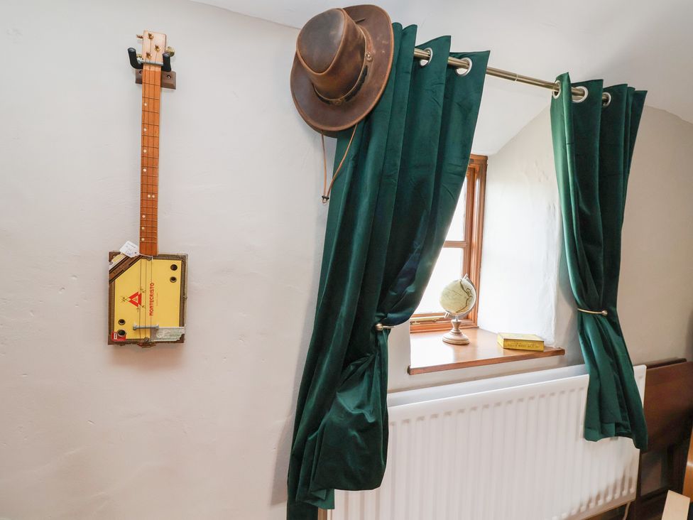 A living room with a guitar and a globe by the window at The Ranch in Prestatyn