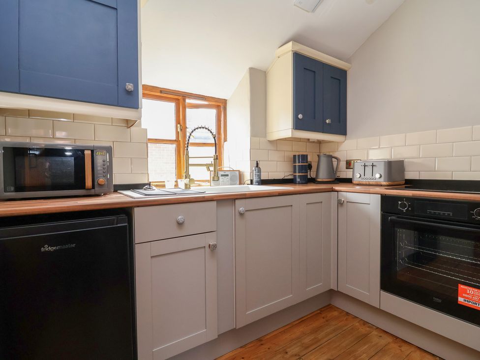 A kitchen with cabinets, sink, and white tiles at The Ranch in Prestatyn