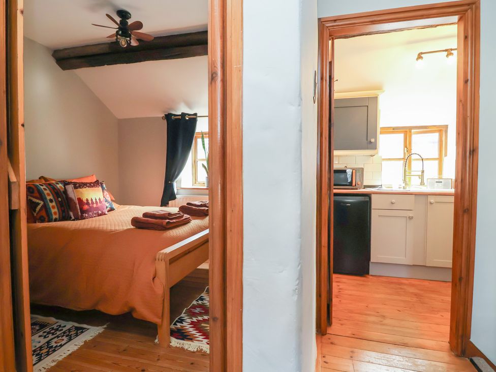 A bedroom with a bed and a view into a kitchen area at The Ranch in Prestatyn