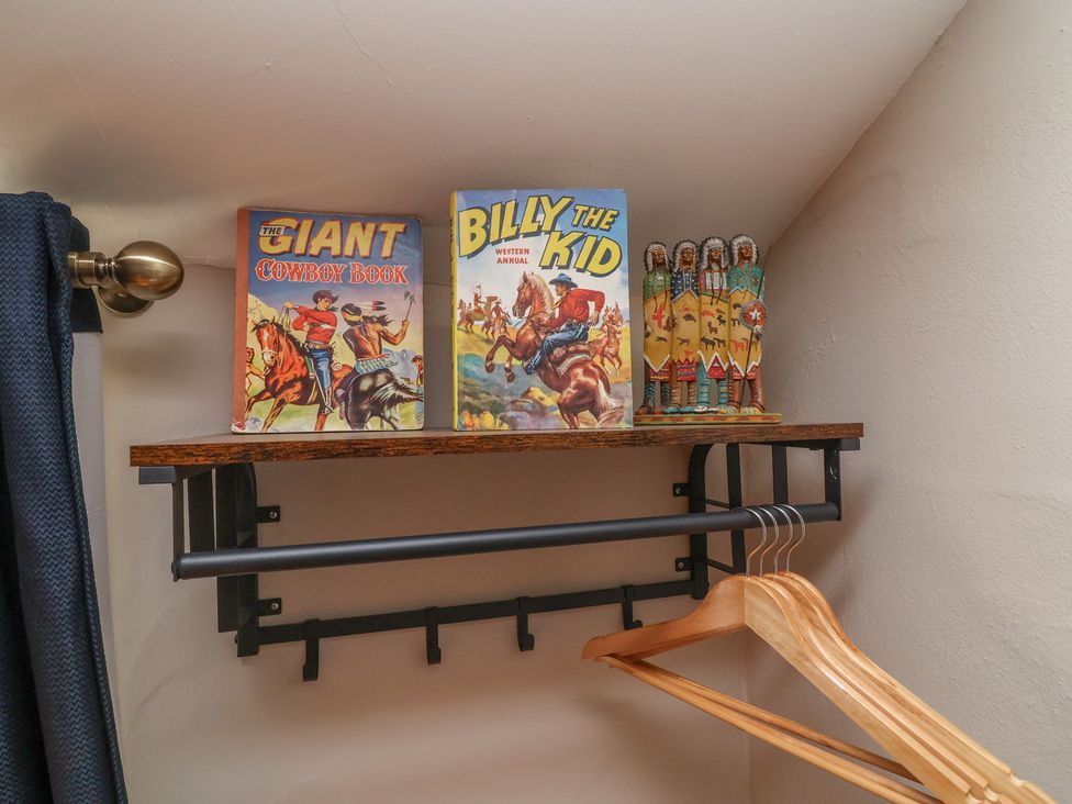 A closet with a shelf displaying books and figurines at The Ranch in Prestatyn
