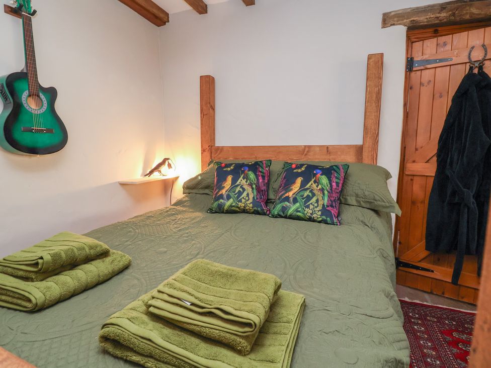 A bedroom with a bed and guitar on the wall at The Ranch in Prestatyn