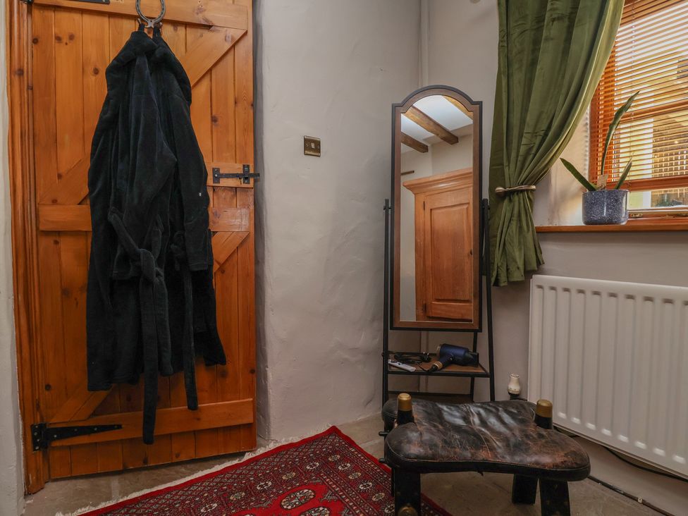 A hallway with a robe on the door and a mirror at The Ranch in Prestatyn