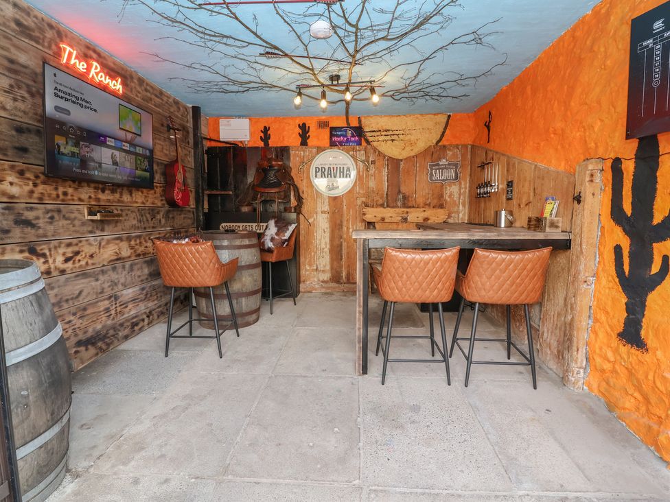 A bar area with wooden furniture and a television at The Ranch in Prestatyn