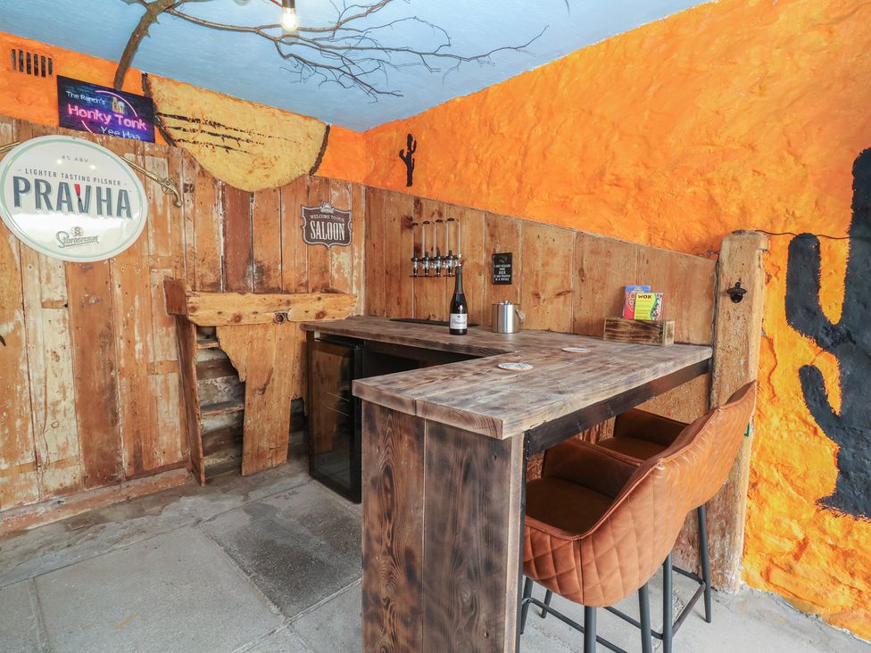 A bar area with wooden decor and stools at The Ranch Prestatyn