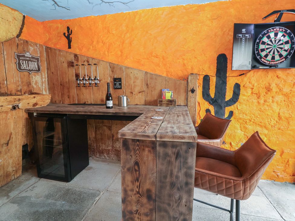 A bar area with a wooden table and a dartboard at The Ranch in Prestatyn