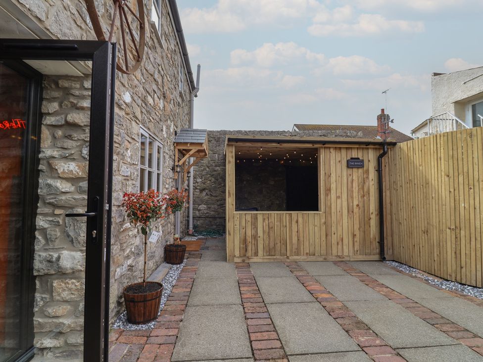 An outdoor courtyard with a wooden shed and stone walls at The Ranch in Prestatyn