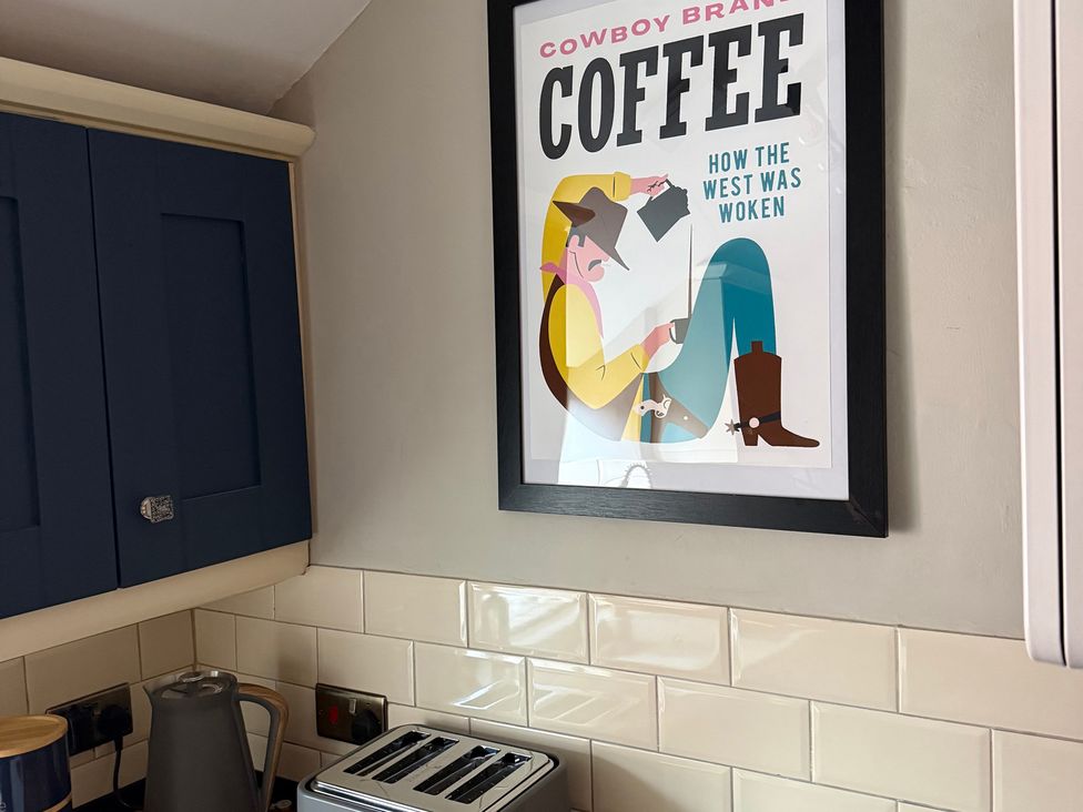 A kitchen with cabinets and a coffee poster at The Ranch in Prestatyn
