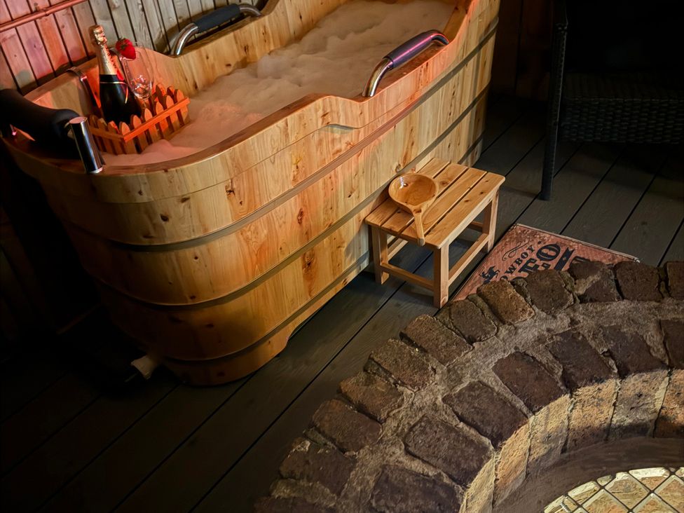 A wooden bathtub with champagne and a stool at The Ranch in Prestatyn