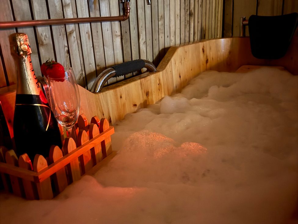 A bathtub with champagne, glass, and a strawberry at The Ranch in Prestatyn