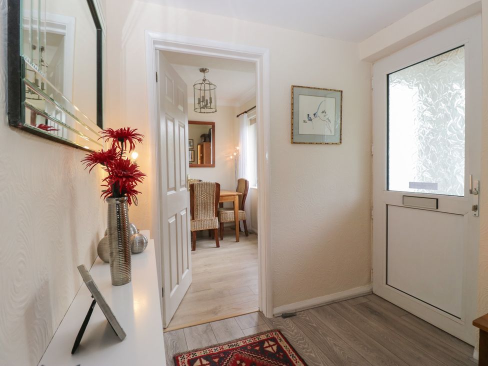 A hallway with a mirror and flowers at Apple Byrd in Kendal