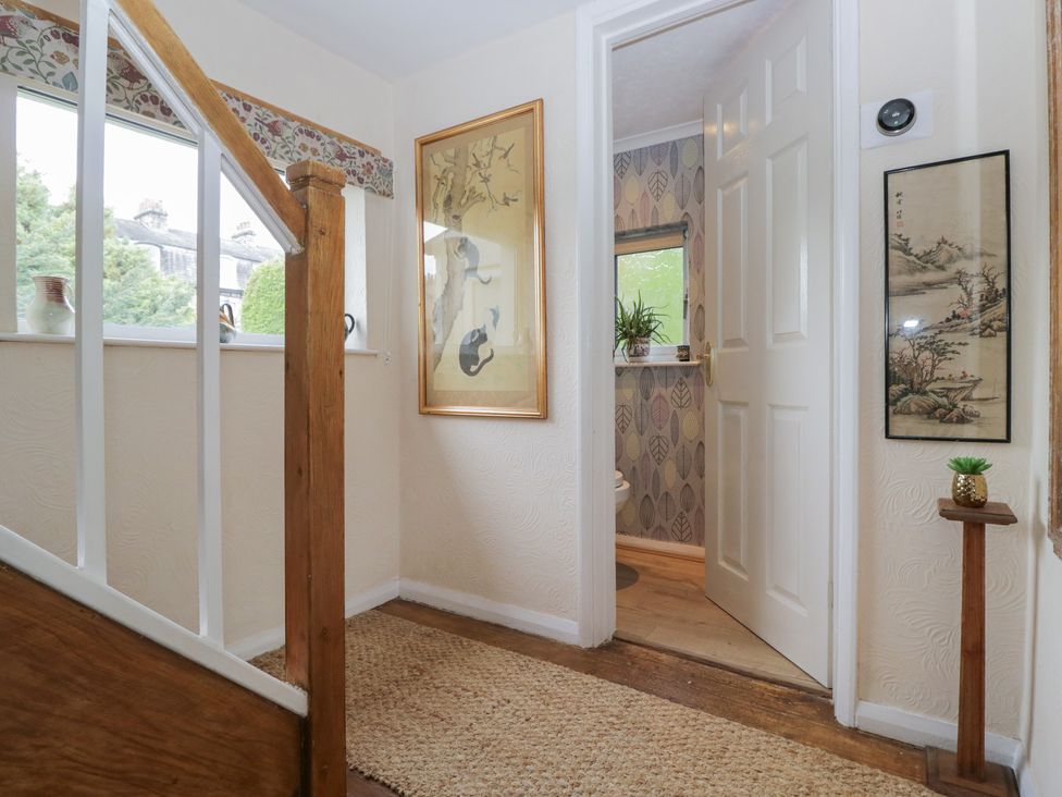 A hallway with a staircase and framed artwork at Apple Byrd in Kendal