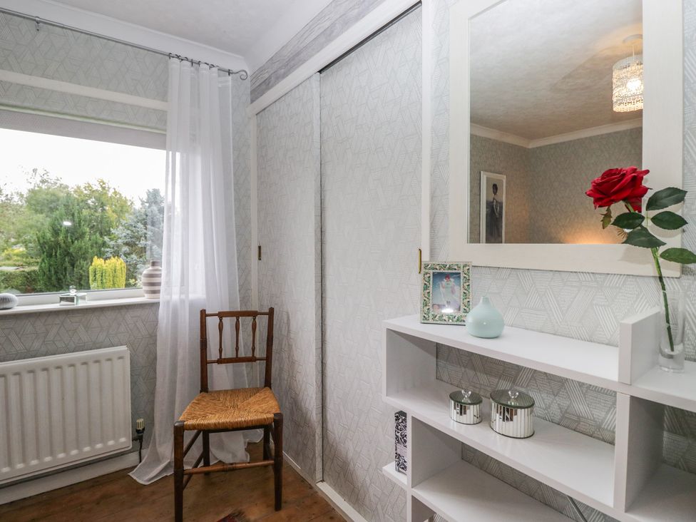 A room with a chair, shelf, and mirror at Apple Byrd in Kendal