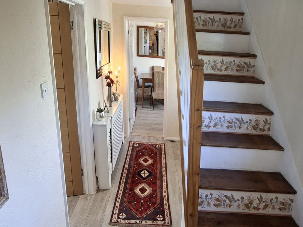A hallway with a staircase and a console table at Apple Byrd in Kendal