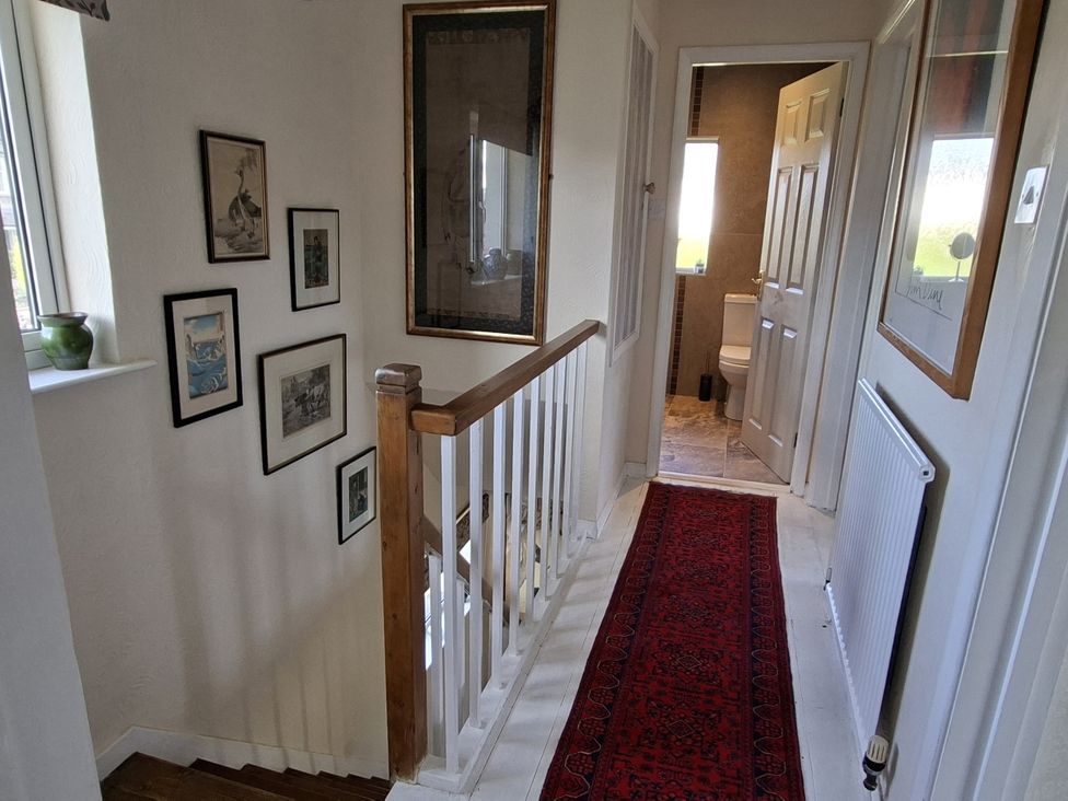 A hallway with a staircase and pictures on the wall at Apple Byrd in Kendal