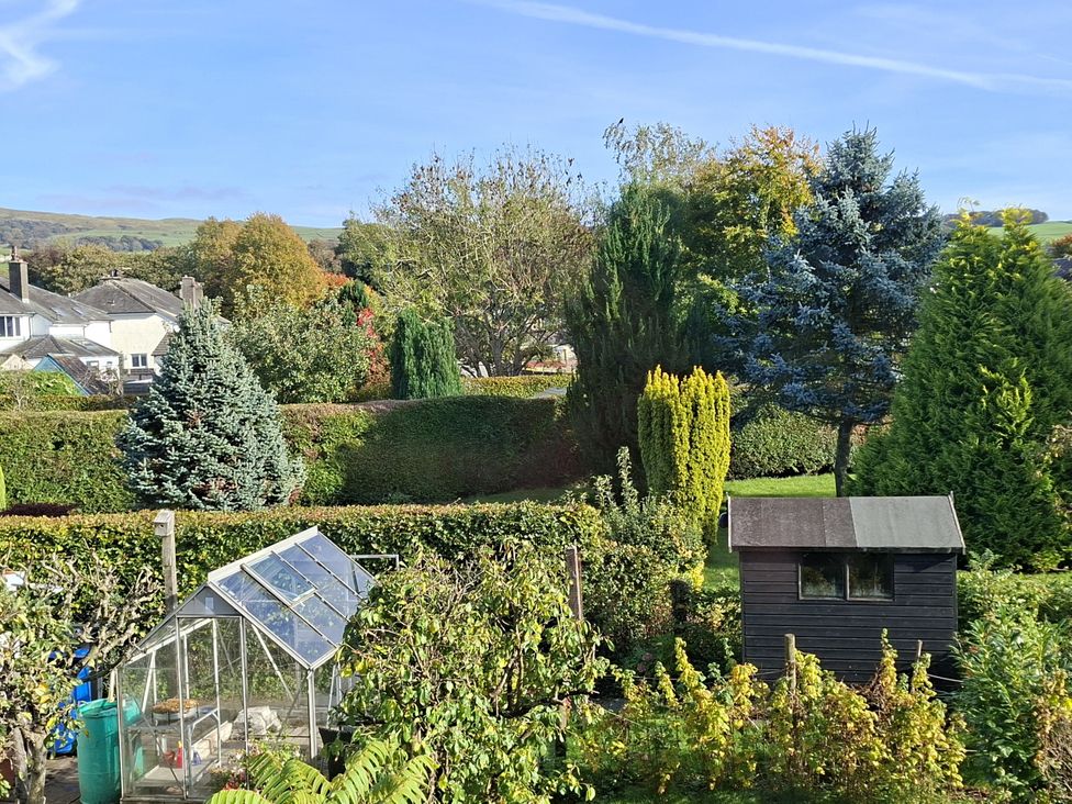 A garden with a greenhouse and shed at Apple Byrd in Kendal