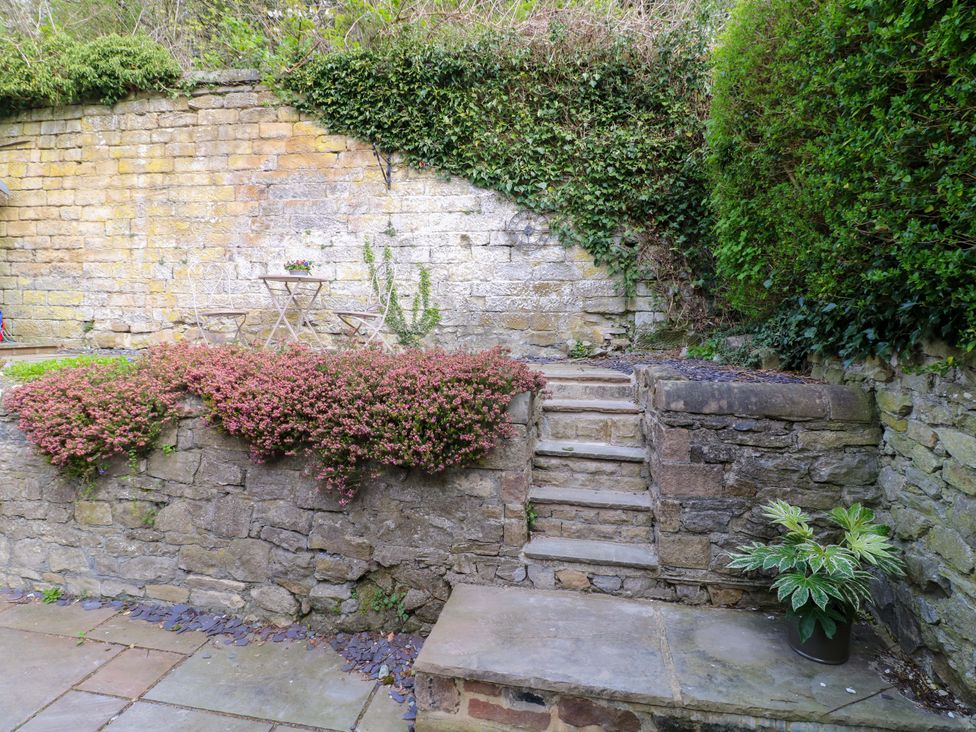 A garden with a stone wall and a table and chairs at 9 New Lumford