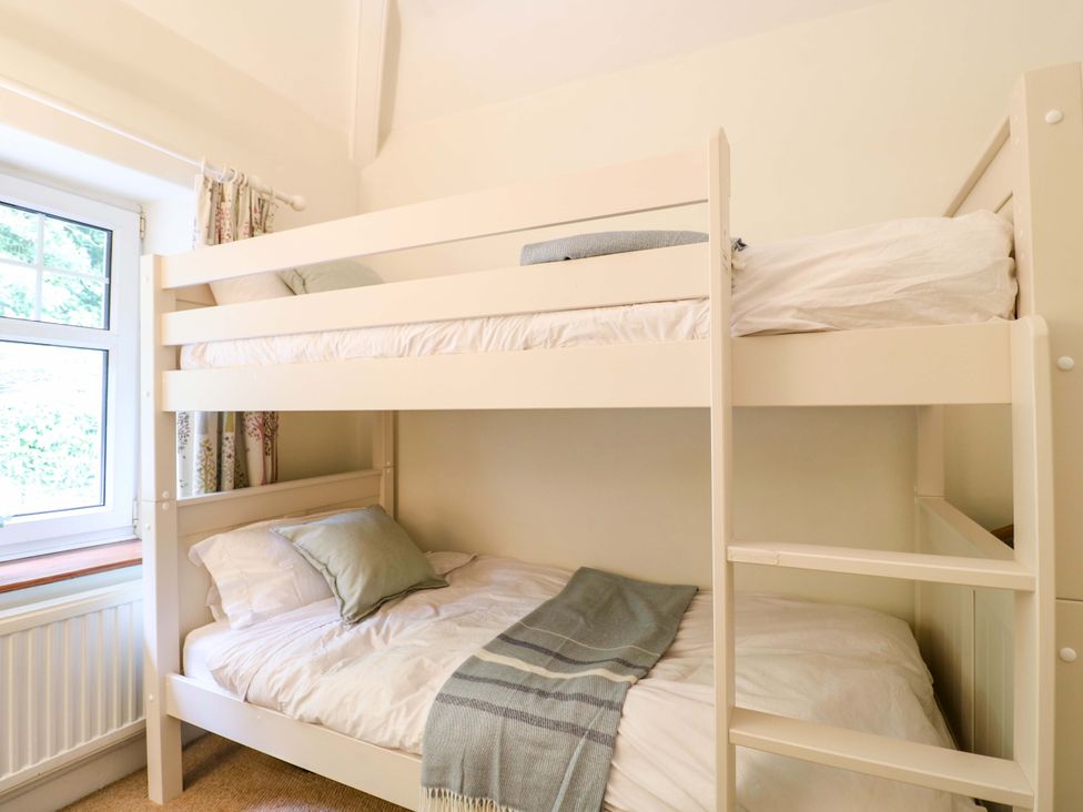 A bedroom with a bunk bed and window at Lumford Mill Cottage, Bakewell