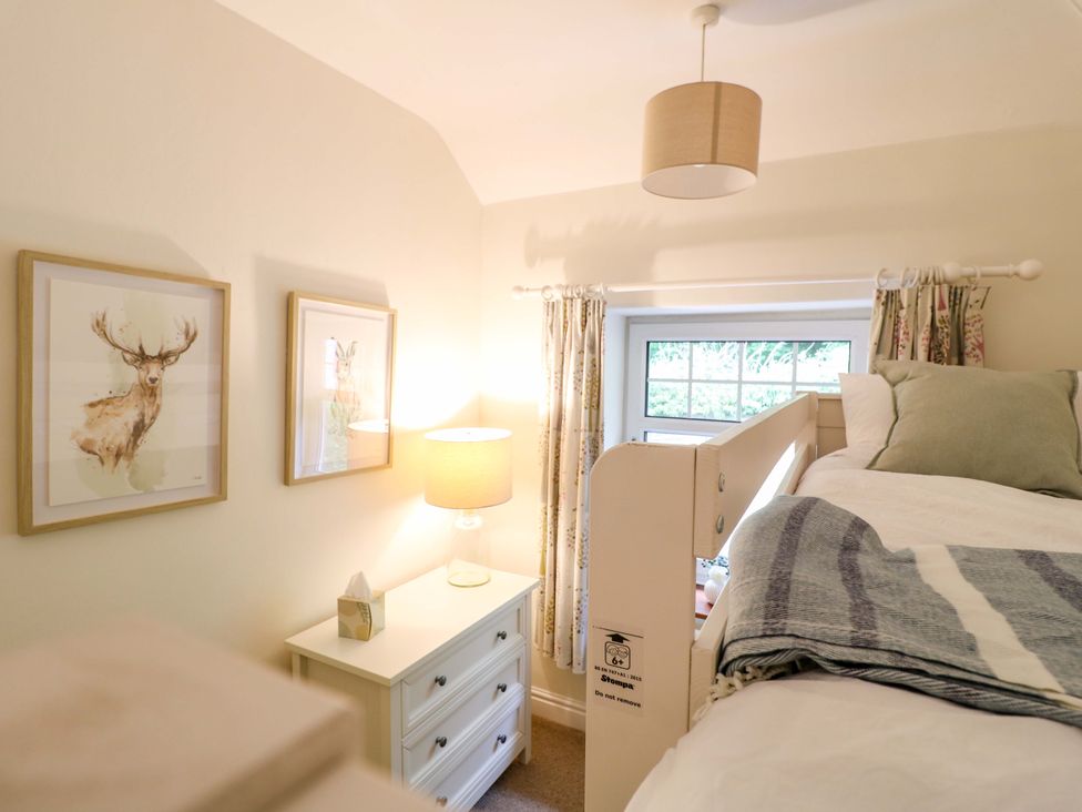 A bedroom with a bed, dresser, and lamp at Lumford Mill Cottage Bakewell