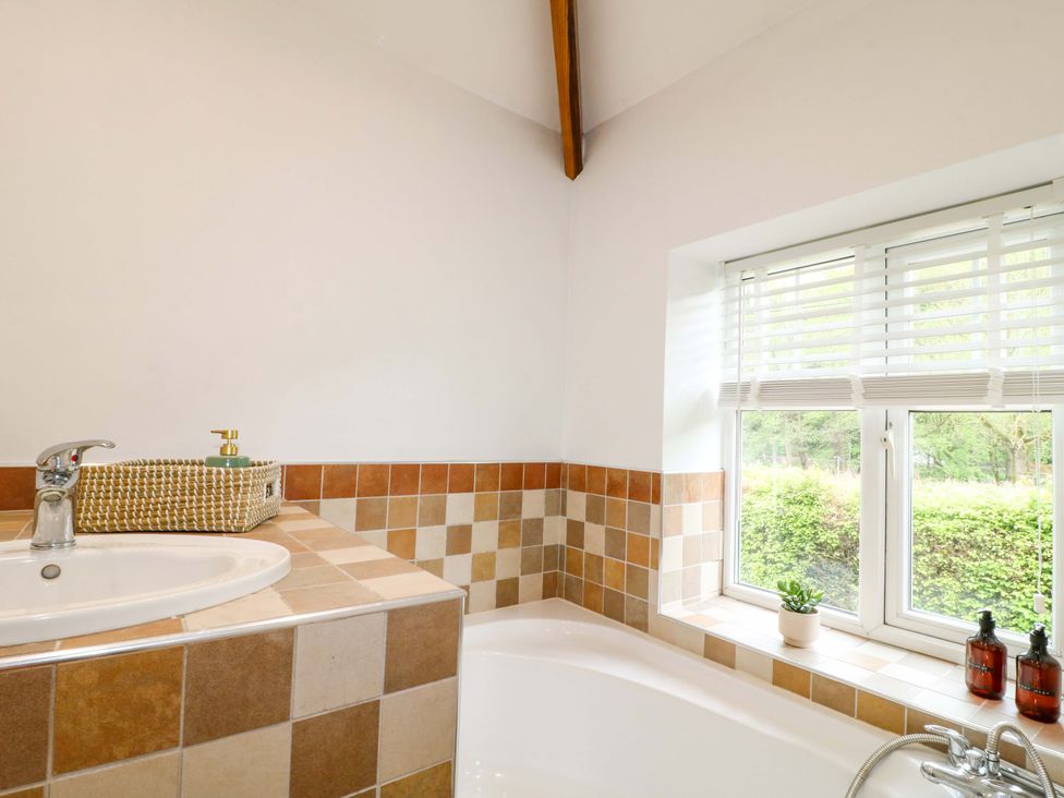 A bathroom with a bath and sink at Lumford Mill Cottage Bakewell