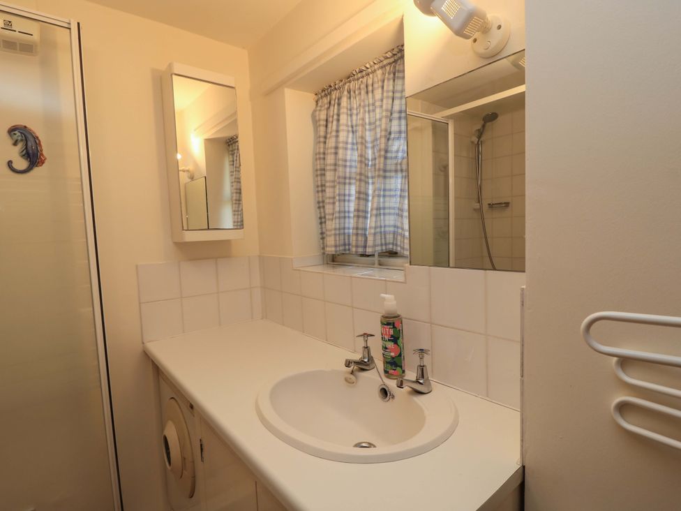 A bathroom with a sink and mirror at Plush Cottage in Dorchester