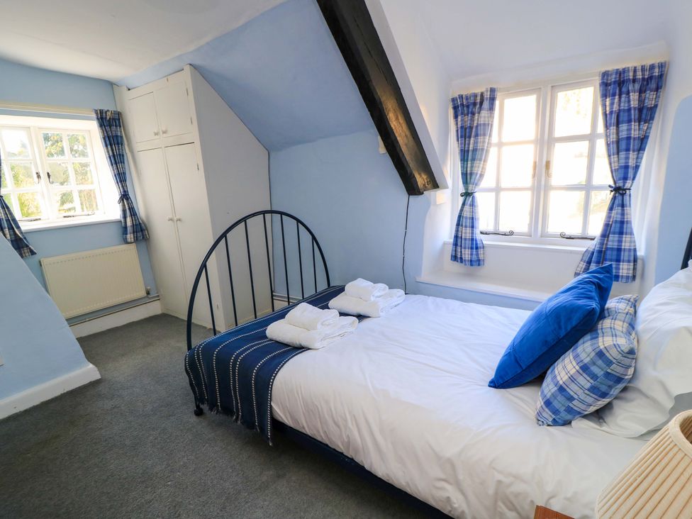 A bedroom with a bed, wardrobe, and window at Plush Cottage in Dorchester