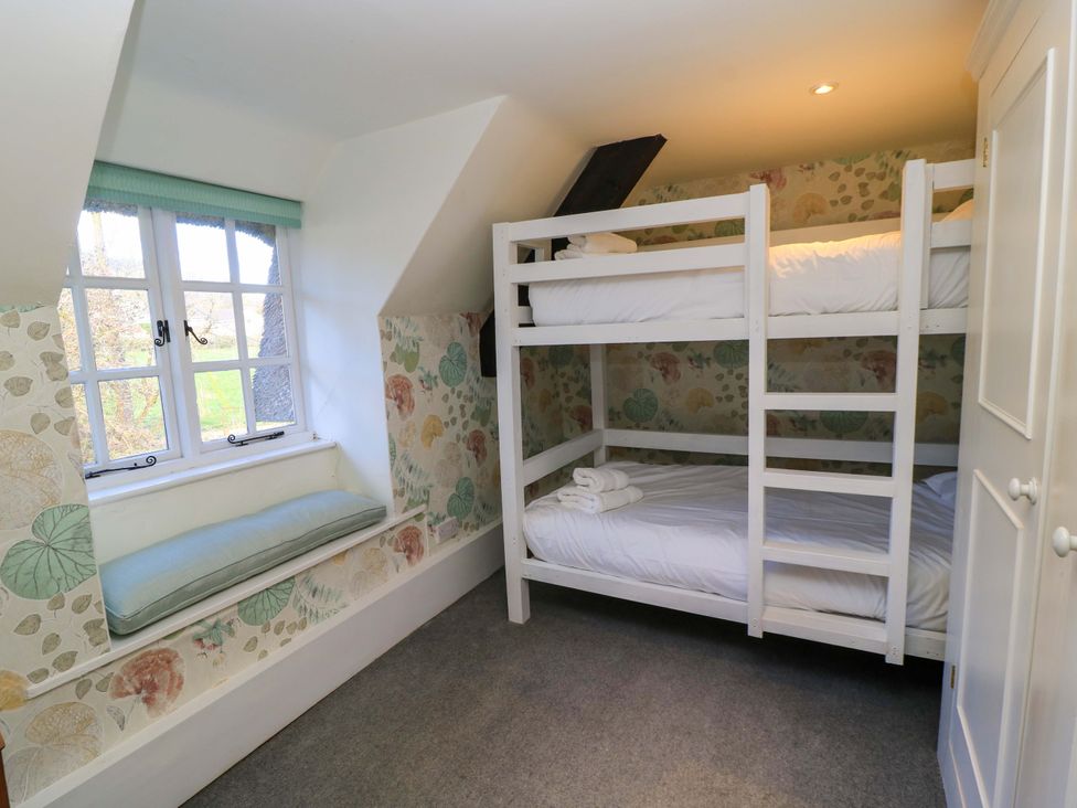A bedroom with a bunk bed and window seat at Plush Cottage in Dorchester