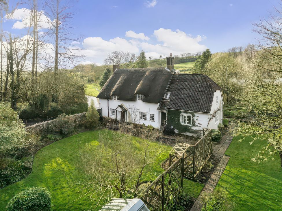A house with a thatched roof and garden at Plush Cottage near Hazelbury Bryan
