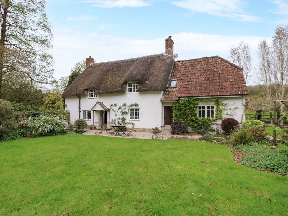 A cottage with a thatched roof and a garden at Plush Cottage in Plush