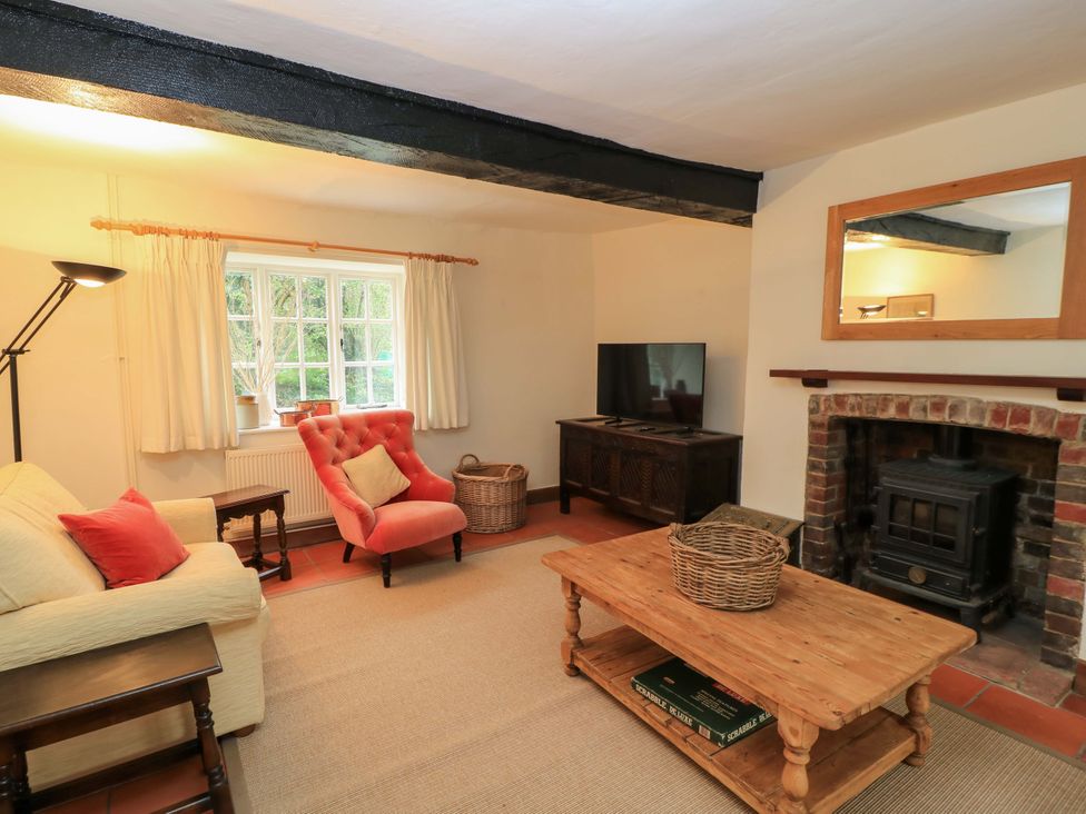 A living room with a sofa, television, and fireplace at Plush Cottage in Plush