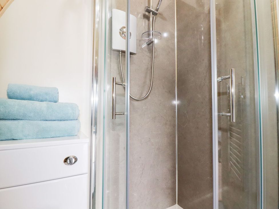A bathroom with a shower and folded towels at Sam in Polgooth