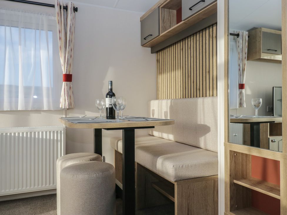A dining area with a table and wine bottle in Mobility Friendly Caravan St Bees