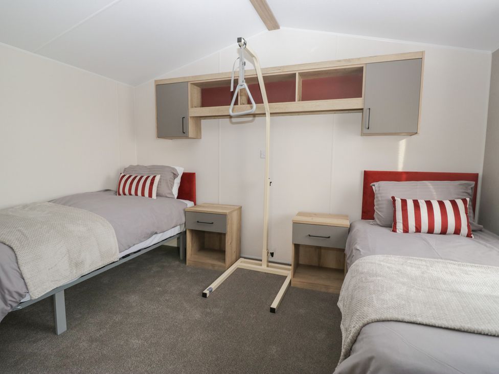 A bedroom with two beds and storage at Mobility Friendly Caravan in St Bees