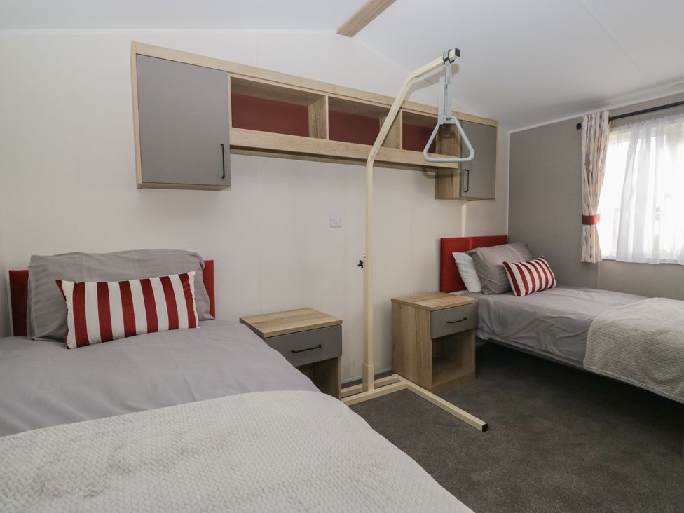 A bedroom with two beds and a wall shelf at Mobility Friendly Caravan in St Bees