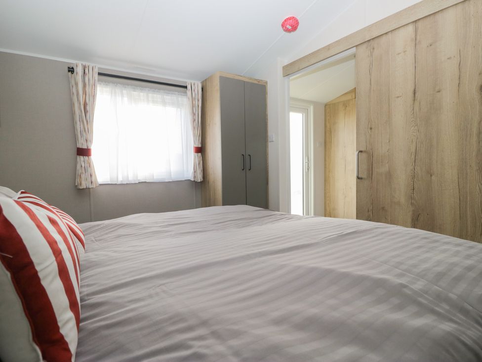 A bedroom with a bed and wardrobe at Mobility Friendly Caravan in St Bees