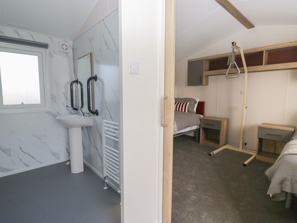 A bathroom with a washbasin and a bedroom with a bed at Mobility Friendly Caravan St Bees