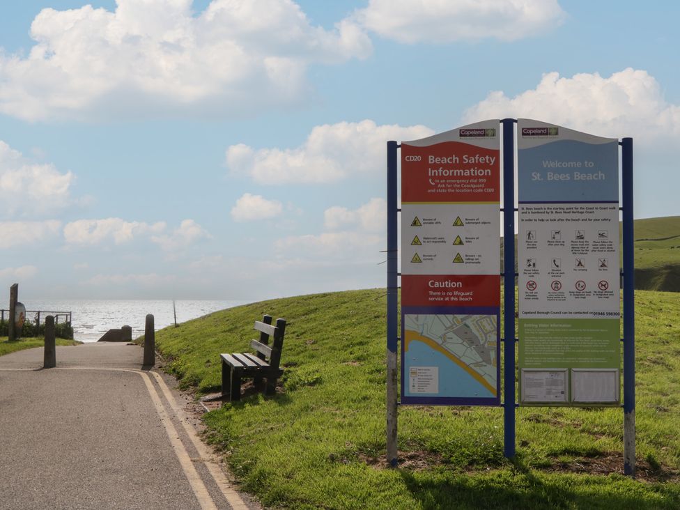 Beach safety information signs and a bench at St Bees Beach