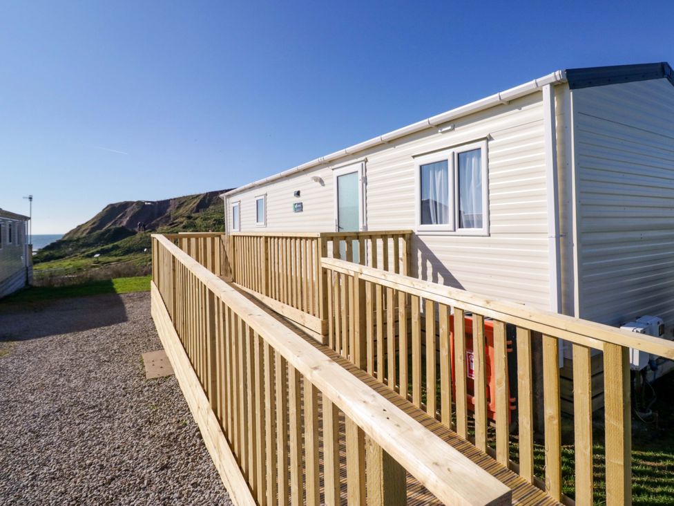 A caravan with a wooden deck overlooking the coast at Guillemot St Bees