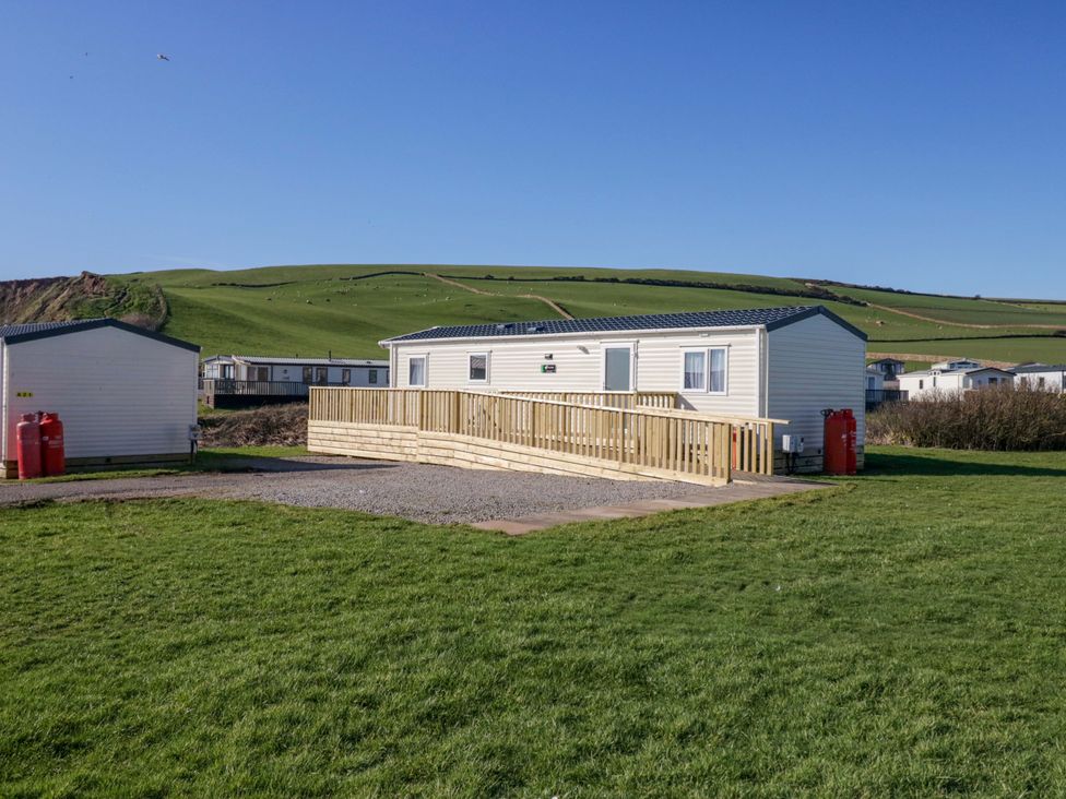 A caravan with a deck on a grassy area at Guillemot in St Bees