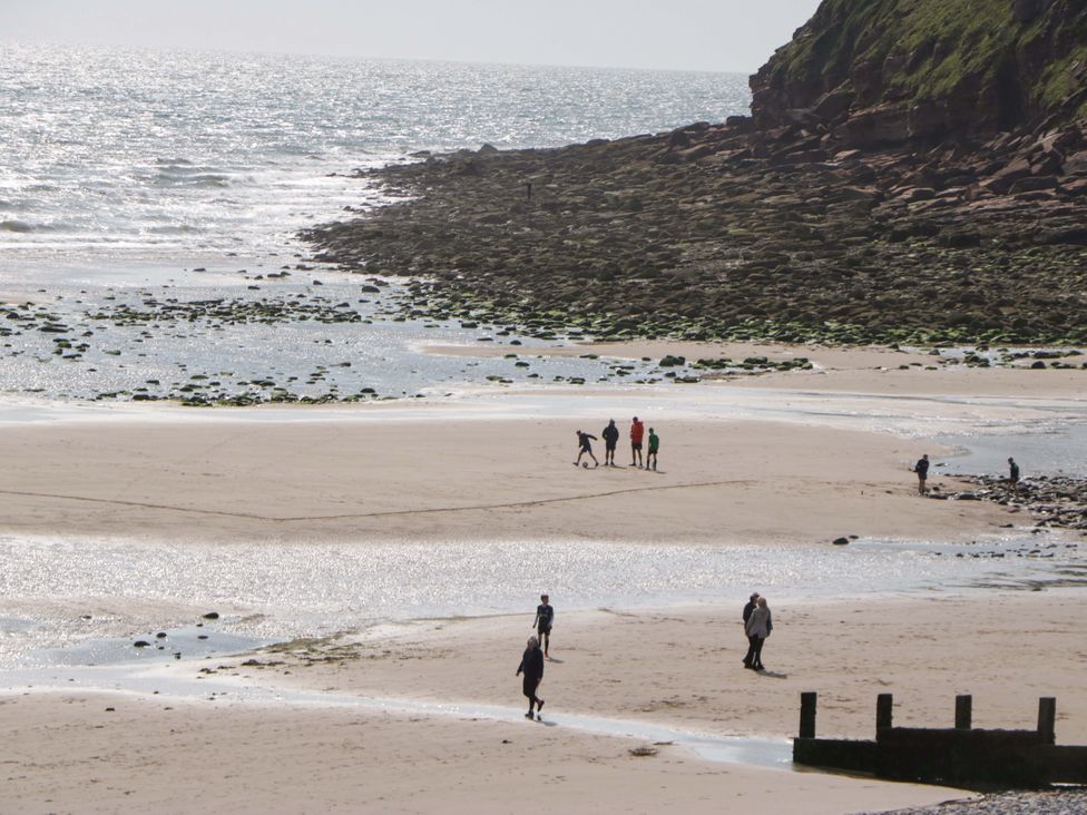 A beach with people walking and playing at Guillemot in St Bees
