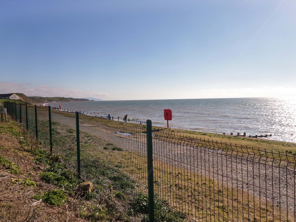 A shoreline with a fence and people walking at Guillemot St Bees