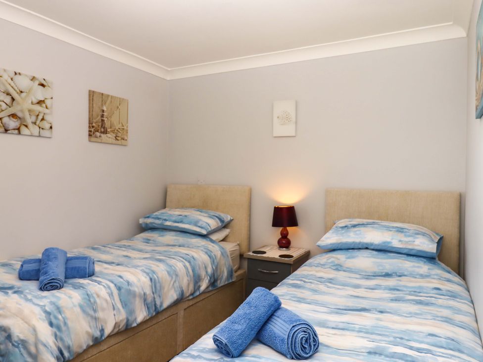 A bedroom with two single beds and a lamp at Beachside