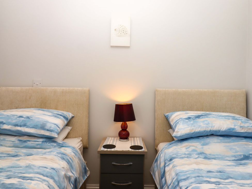 A bedroom with two beds and a lamp on a nightstand at Beachside