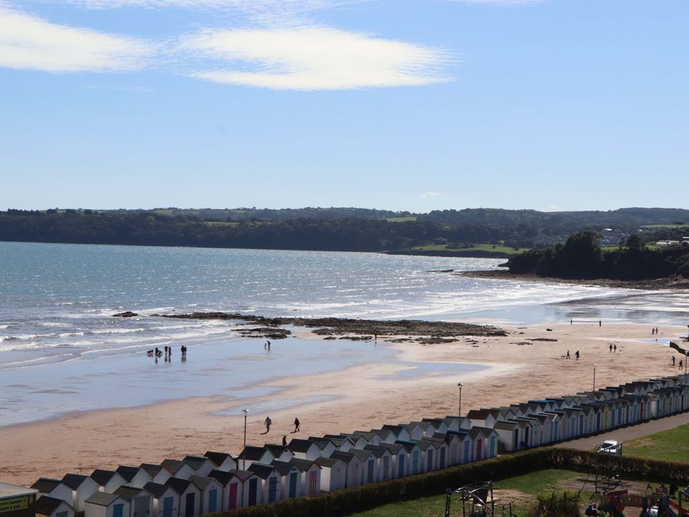 A beach scene with beach huts and people walking on the sand at Beachside