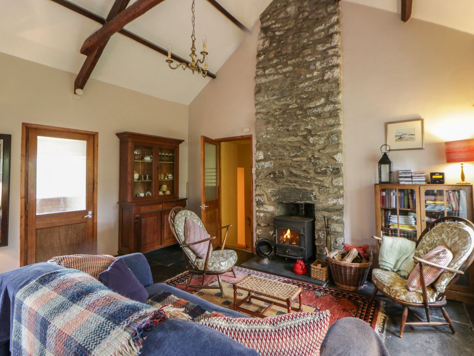 A living room with a stone fireplace and wooden furniture at Tyn Y Fron in Brynherbert near Llanrhystud