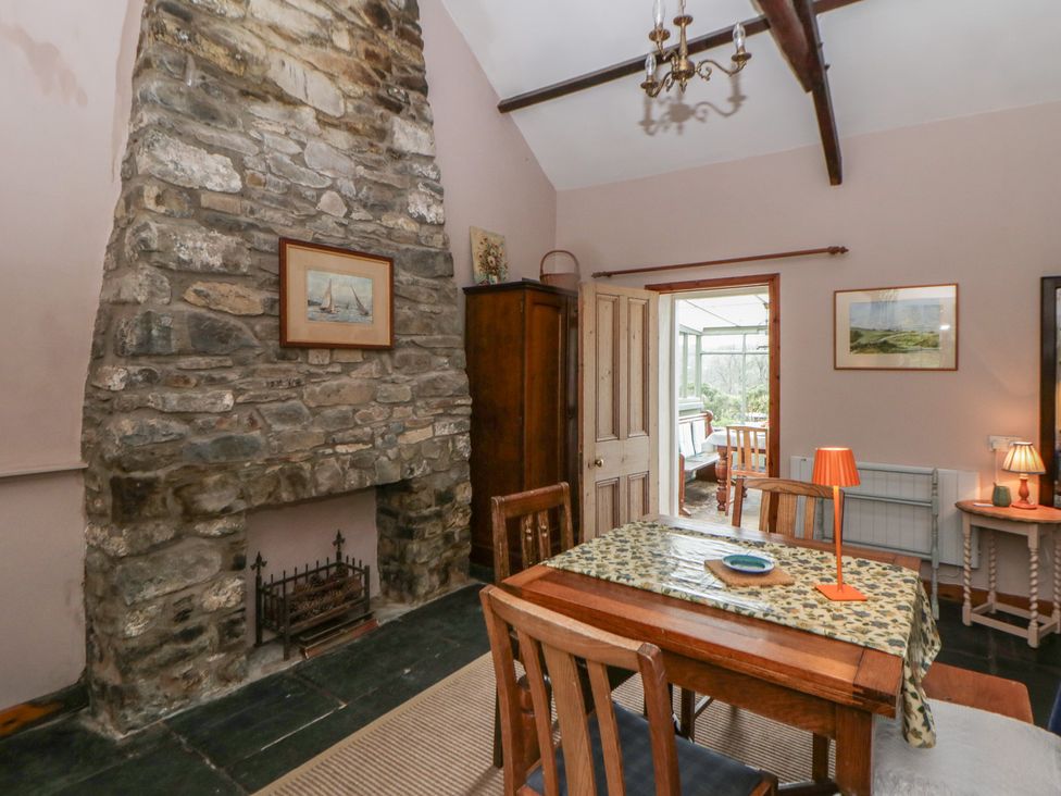 A dining room with a stone fireplace and wooden table at Tyn Y Fron Brynherbert near Llanrhystud