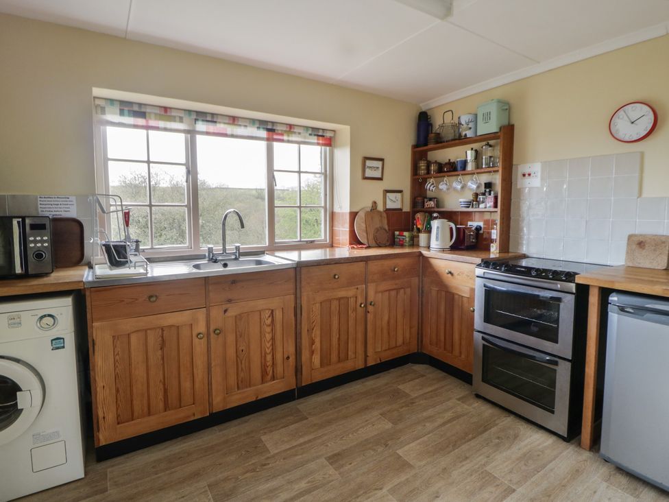 A kitchen with wooden cupboards and appliances at Tyn Y Fron in Brynherbert near Llanrhystud