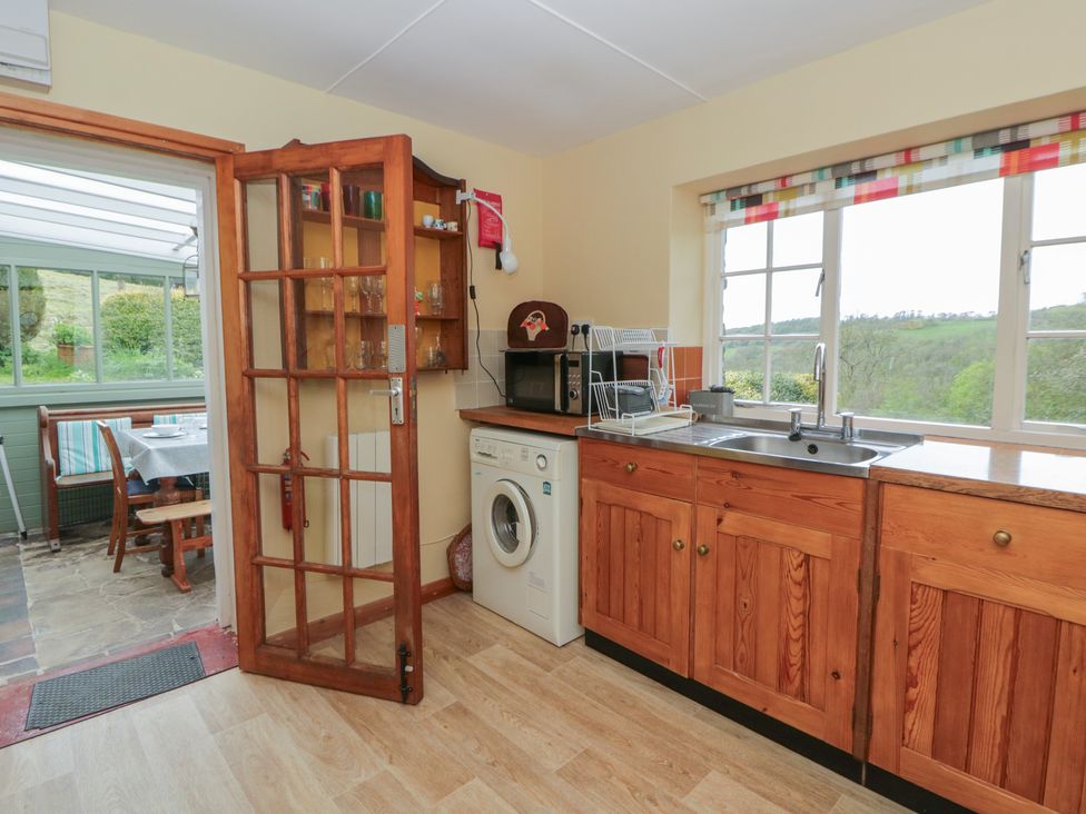A kitchen with a washing machine and sink at Tyn Y Fron in Brynherbert near Llanrhystud